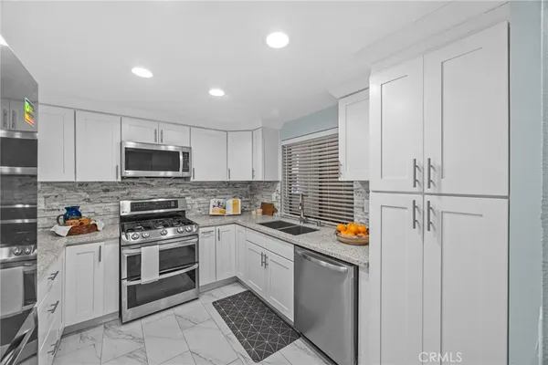 a kitchen with stainless steel appliances granite countertop a stove a sink and a microwave