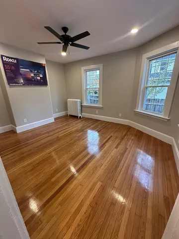a view of empty room with wooden floor and fan
