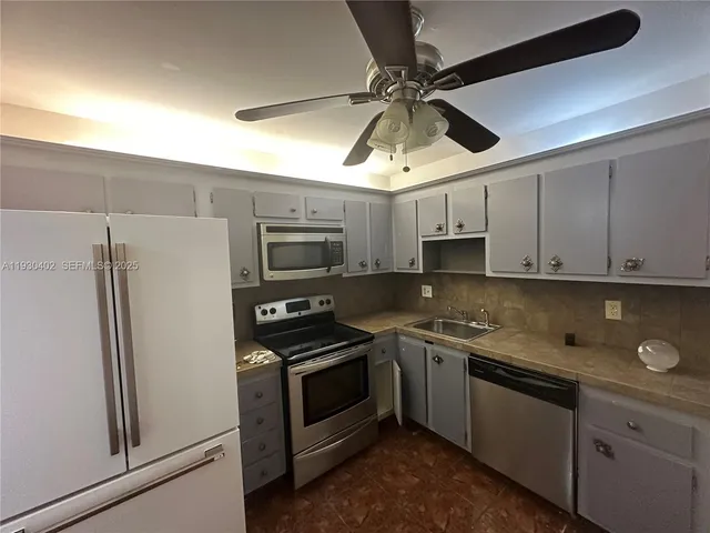 a kitchen with stainless steel appliances a refrigerator a stove and white cabinets