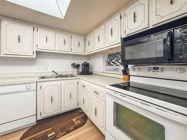 a kitchen with white cabinets stainless steel appliances and sink