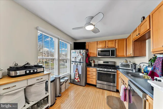 a kitchen with stainless steel appliances granite countertop a refrigerator a stove top oven a sink and dishwasher with wooden floor