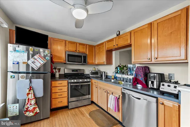 a kitchen with stainless steel appliances granite countertop a stove top oven a sink dishwasher and white cabinets with wooden floor