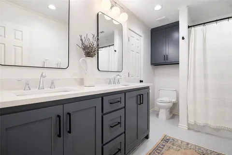 a bathroom with a double vanity sink toilet and mirror