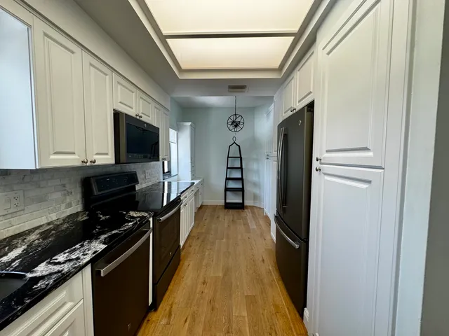 a kitchen with a refrigerator a stove top oven and wooden floor