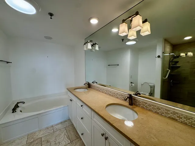 a bathroom with a granite countertop sink a large mirror and a bathtub