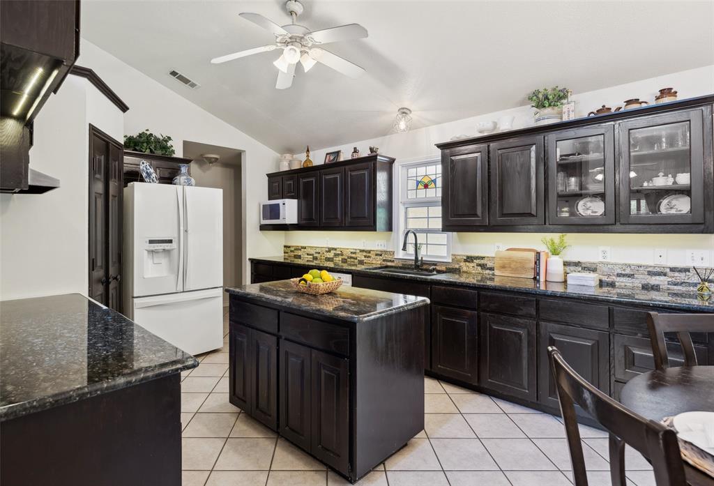 1000 Ballard Road Van Alstyne, TX 75495 - Photo 17 of 40 a kitchen with stainless steel appliances granite countertop a stove top oven a sink dishwasher and a refrigerator with wooden cabinets