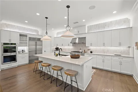 a kitchen with stainless steel appliances kitchen island a table chairs sink and cabinets