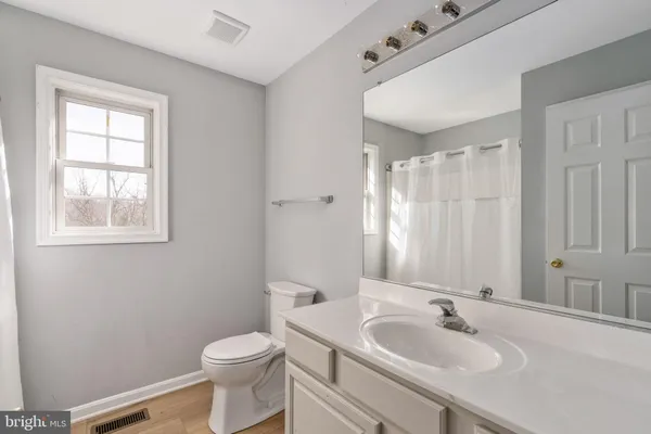 a living room with a couch and a dining table with wooden floor