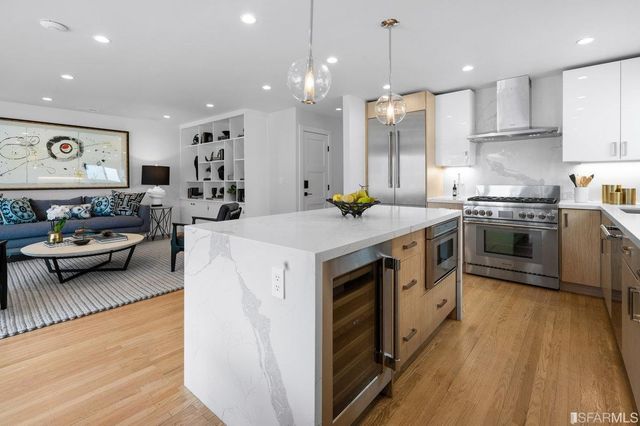 a open kitchen with stainless steel appliances granite countertop a stove a sink dishwasher and a refrigerator with wooden floor