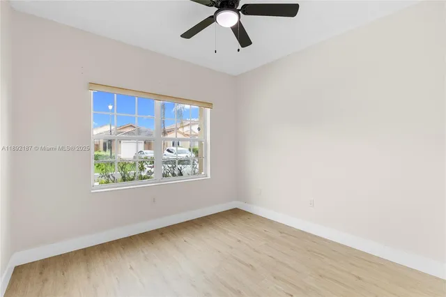 an empty room with wooden floor fan and windows