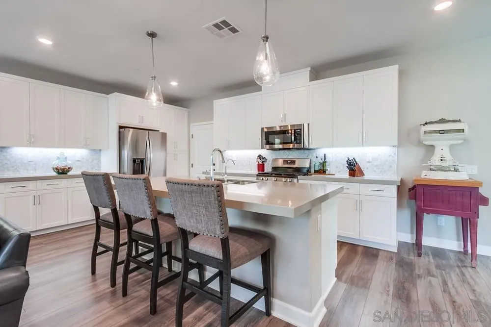 1933 Pascal Court Escondido, CA 92026 - Photo 10 of 52 a kitchen with kitchen island granite countertop a dining table chairs refrigerator and microwave