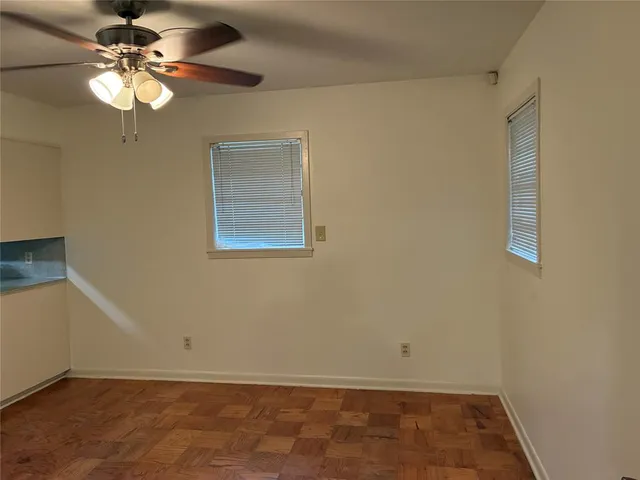an empty room with a chandelier fan and windows
