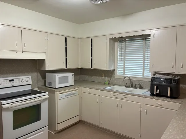 a kitchen with appliances a sink and cabinets