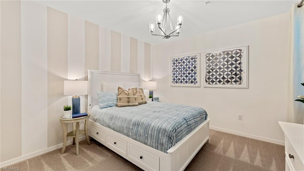 5467 Double Eagle Circle, Unit 3225 Ave Maria, FL 34142 - Photo 18 of 31 a bedroom with a large bed and a chandelier