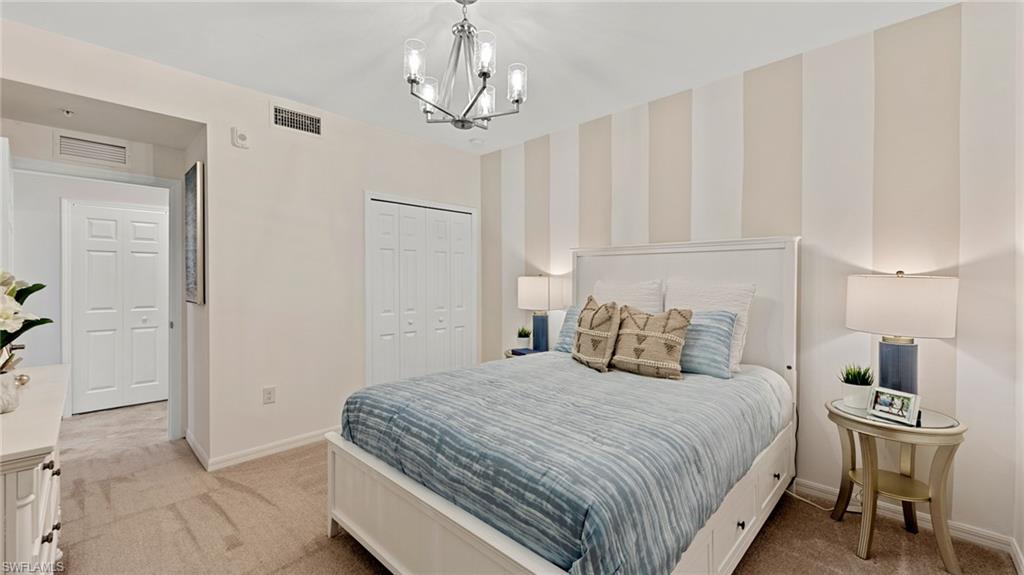5467 Double Eagle Circle, Unit 3225 Ave Maria, FL 34142 - Photo 19 of 31 a bedroom with a large bed and a chandelier