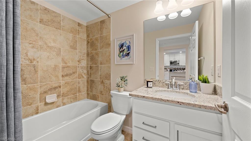 5467 Double Eagle Circle, Unit 3225 Ave Maria, FL 34142 - Photo 20 of 31 a bathroom with a granite countertop sink a toilet a mirror a vanity a bathtub and shower