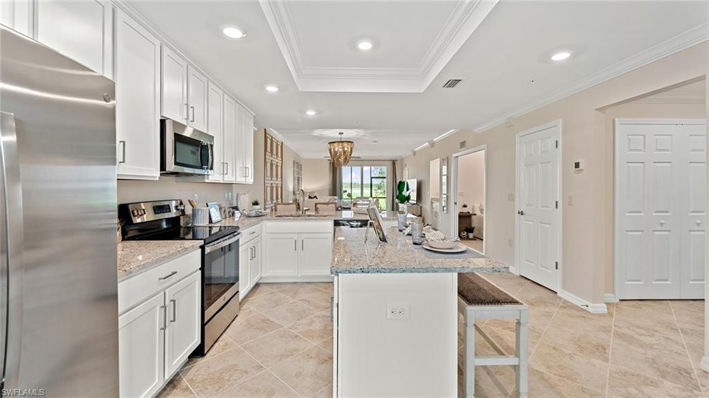5467 Double Eagle Circle, Unit 3225 Ave Maria, FL 34142 - Photo 6 of 31 a kitchen with stainless steel appliances kitchen island granite countertop a stove and a sink