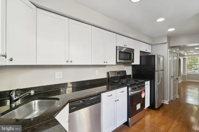 a kitchen with granite countertop a sink stove and refrigerator