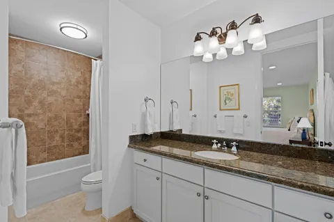 a bathroom with a granite countertop sink a toilet and a mirror