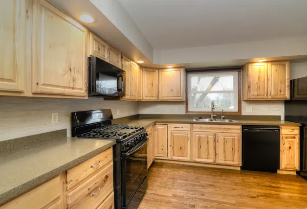 a kitchen with granite countertop a refrigerator and wooden floor