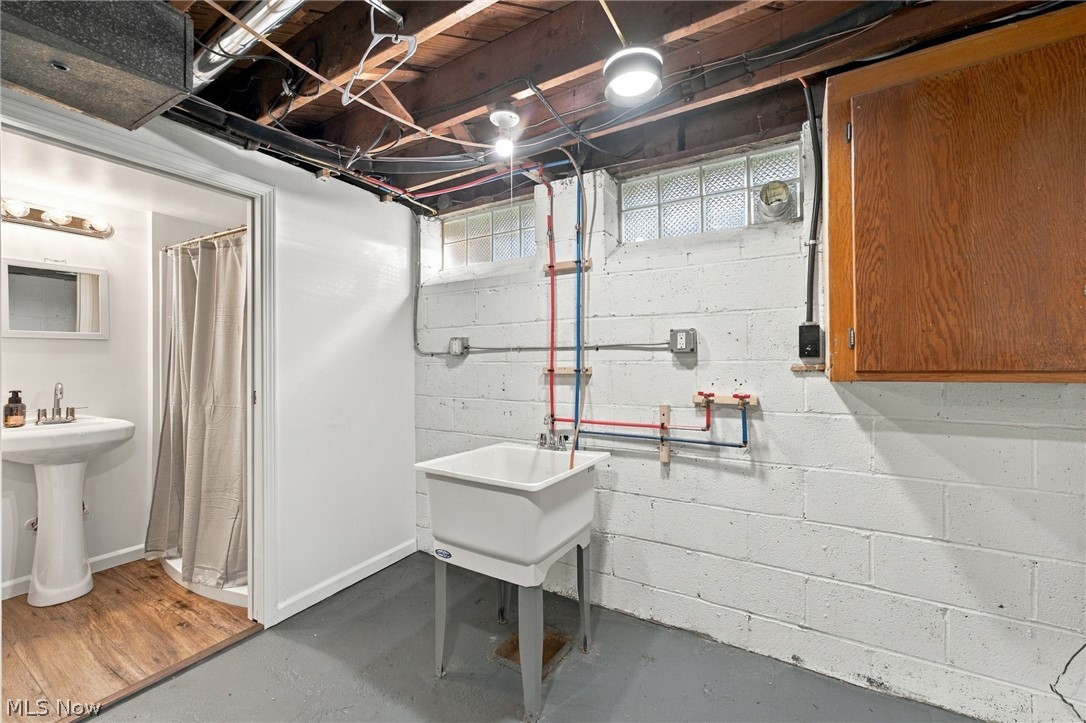 1434 Sunset Road Mayfield Heights, OH 44124 - Photo 35 of 36 Utility area featuring a pedestal sink, wood-finish flooring, a utility sink, and wall-mounted cabinetry