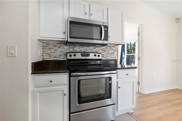 a kitchen with granite countertop white cabinets stainless steel appliances and a sink