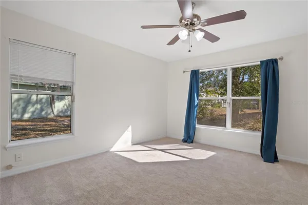 an empty room with windows and ceiling fan