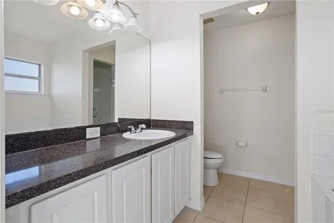 a bathroom with a granite countertop sink a toilet and a mirror