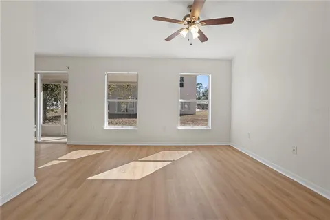 an empty room with windows and fan