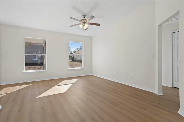 a view of an empty room with a window and wooden floor