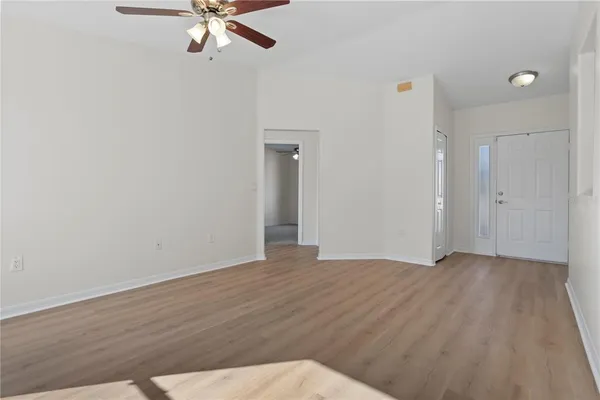an empty room with wooden floor and fan