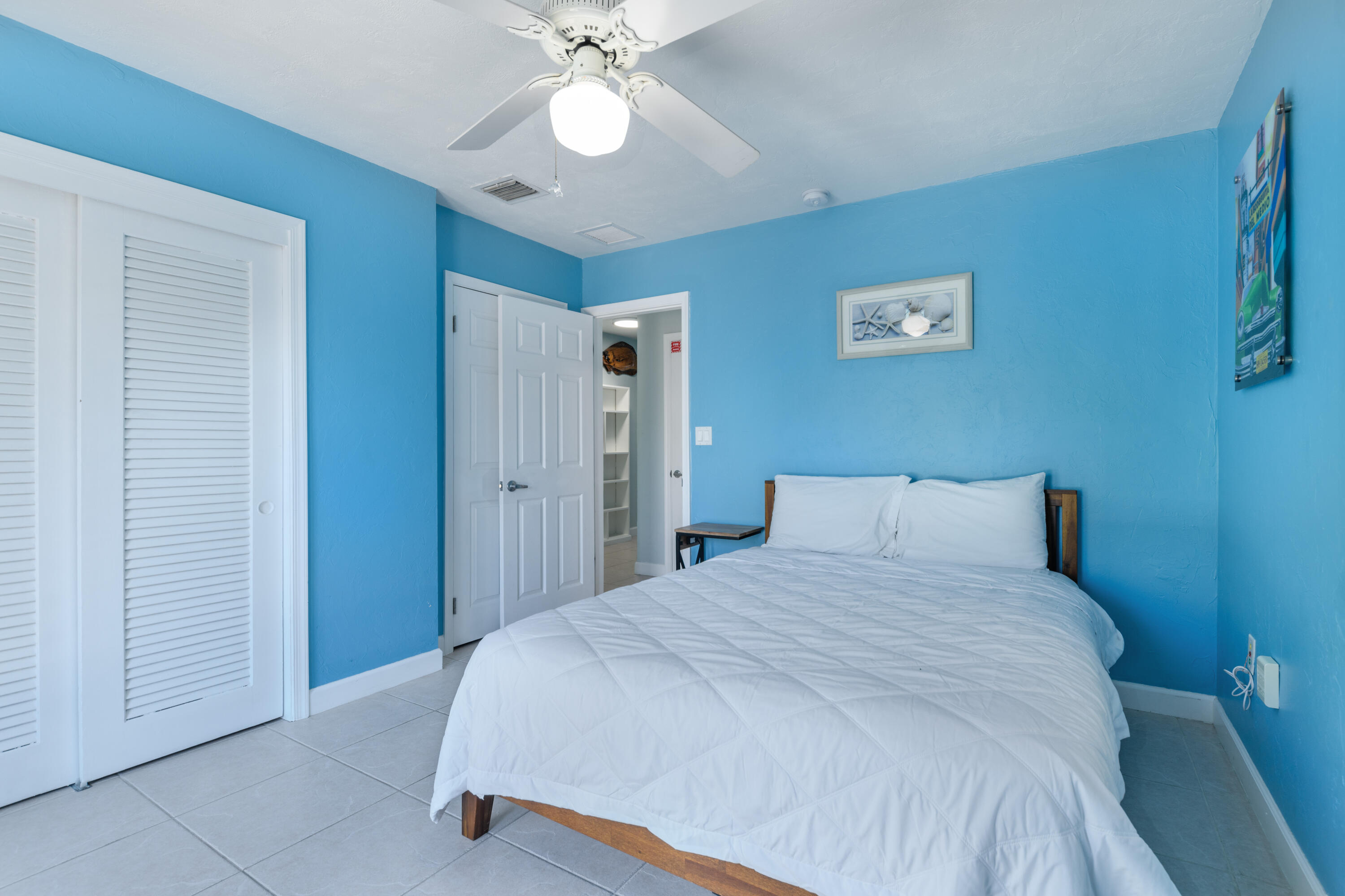 8260 Aviation Boulevard Marathon, FL 33050 - Photo 24 of 36 a bedroom with a large bed and a chandelier