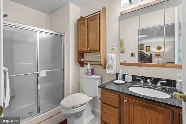 a bathroom with a granite countertop sink toilet and shower