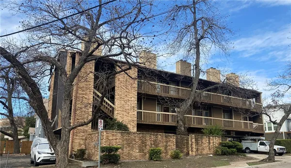 a front view of a building with streets and trees