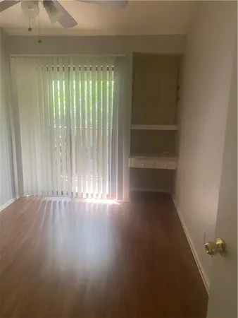 a view of an empty room with wooden floor and closet