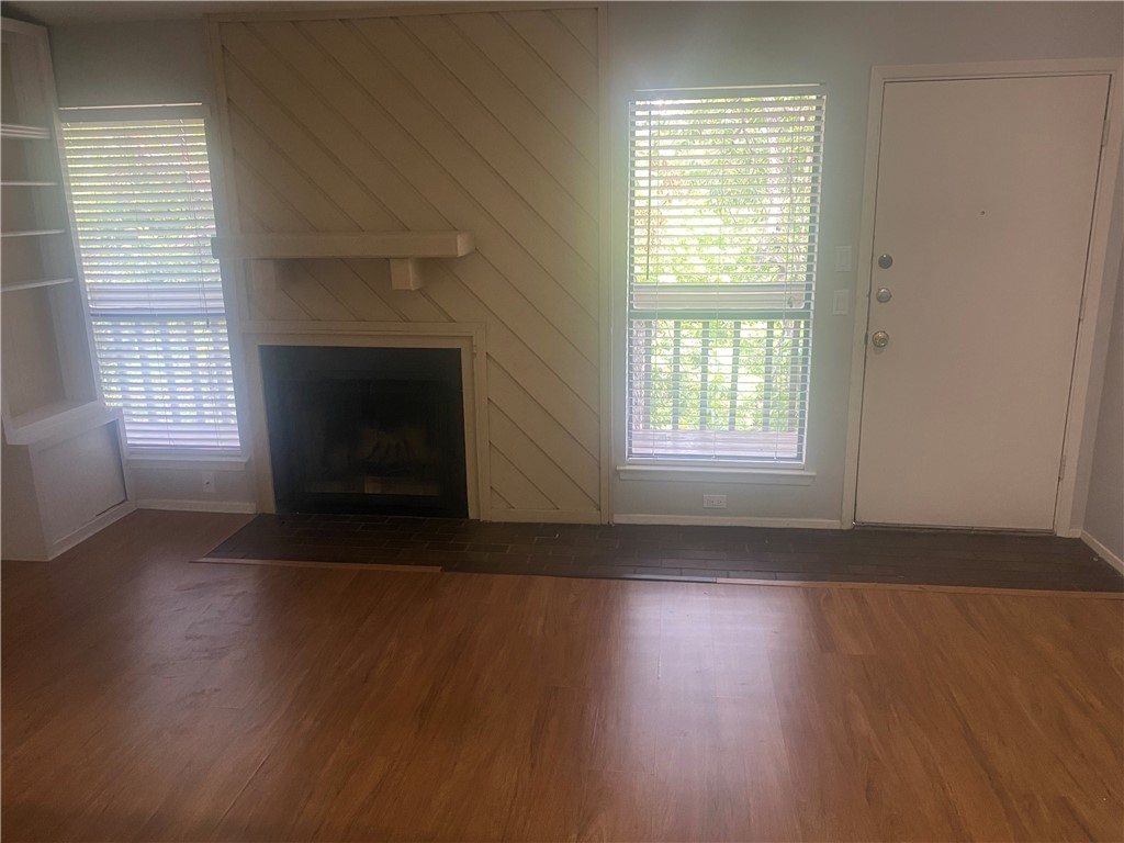 612 Park Place, Unit 303 Austin, TX 78705 - Photo 5 of 26 an empty room with wooden floor fireplace and windows