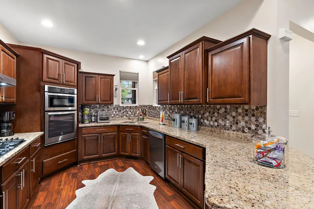 a kitchen with stainless steel appliances granite countertop a refrigerator a stove and a dining table with wooden floors