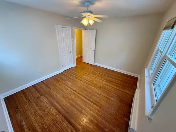 a view of an empty room with chandelier and wooden floor
