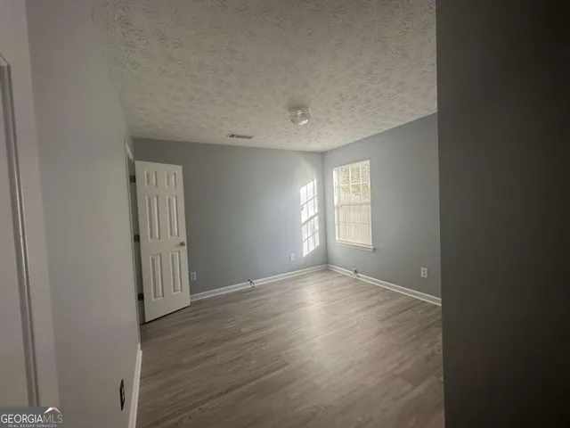 a view of an empty room with wooden floor and windows