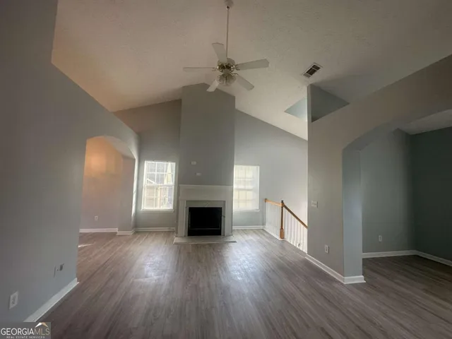 an empty room with wooden floor a fireplace and windows