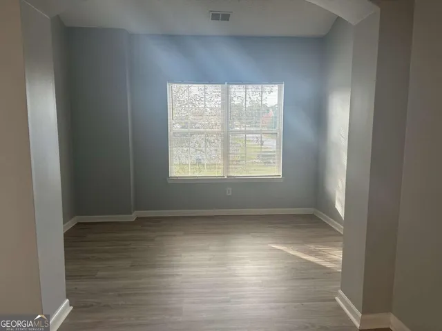 an empty room with wooden floor and windows