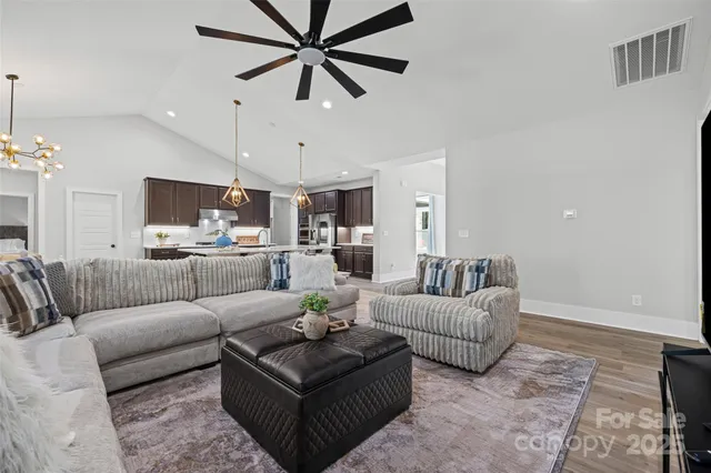 a living room with furniture kitchen view and a chandelier