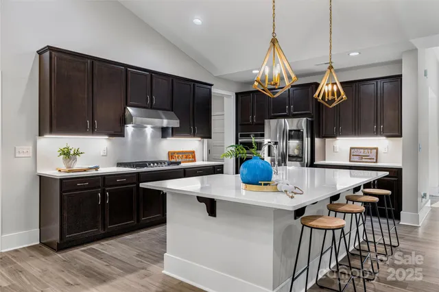 a kitchen with stainless steel appliances granite countertop a sink a stove and a wooden floors