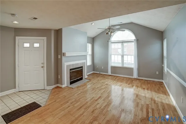 an empty room with windows fireplace and wooden floor