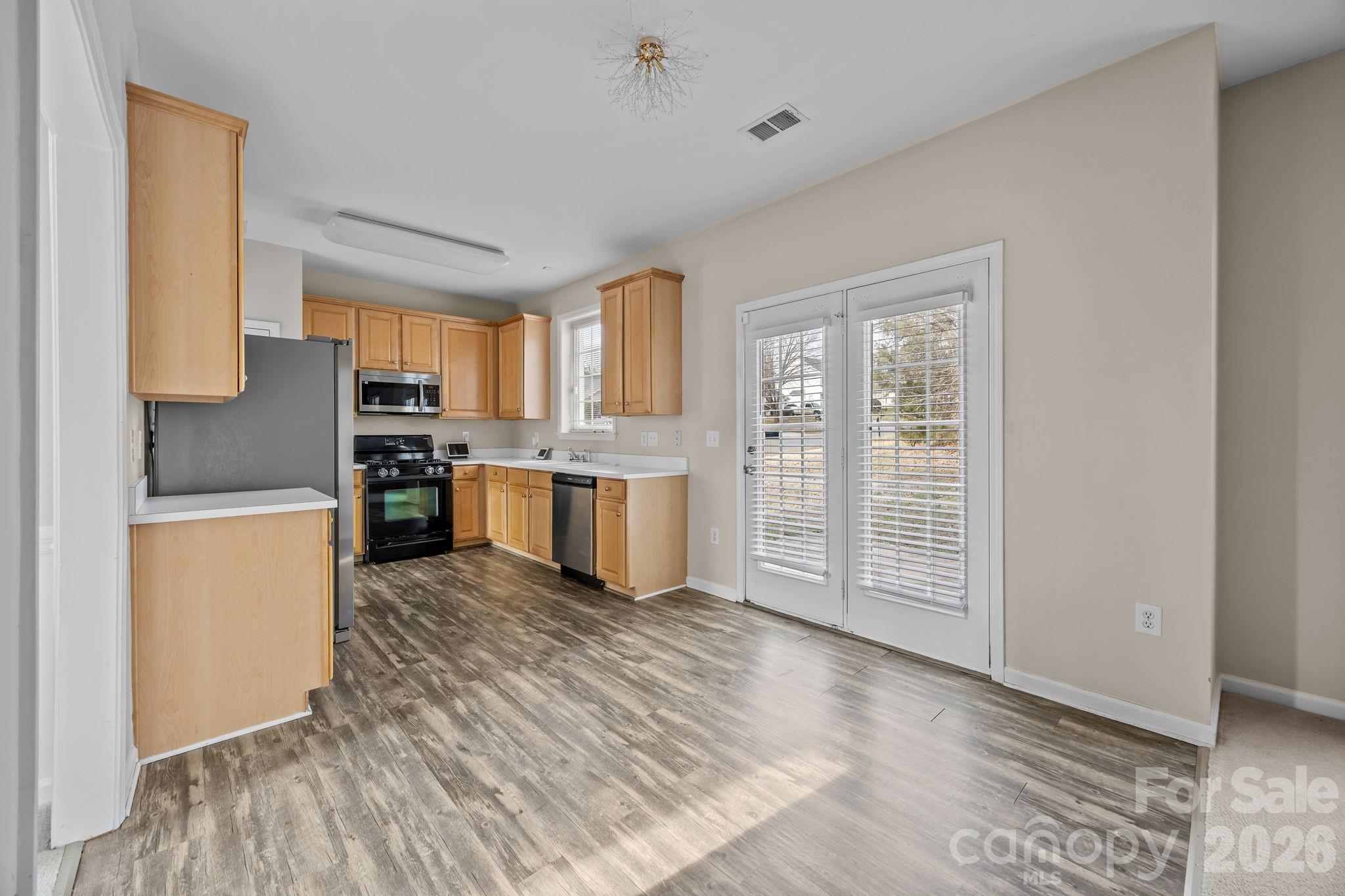 3203 Arklow Road Charlotte, NC 28269 - Photo 11 of 44 a kitchen with stainless steel appliances granite countertop a refrigerator a stove top oven and a sink with wooden floors