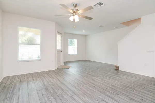 an empty room with wooden floor and windows
