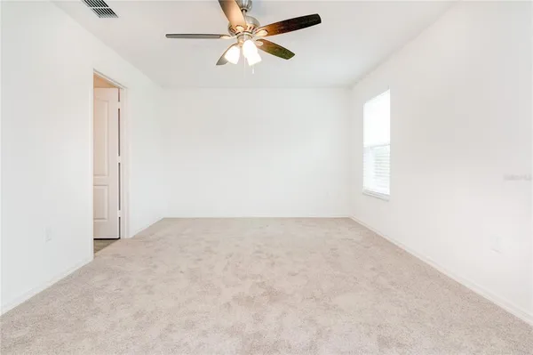 an empty room with windows and fan