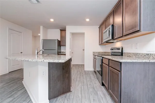 a kitchen with stainless steel appliances granite countertop a stove a sink dishwasher and a microwave oven with wooden floor