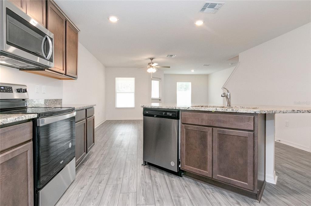 1668 Wynford Circle Tavares, FL 32778 - Photo 8 of 30 a kitchen with stainless steel appliances granite countertop a stove a sink dishwasher and a microwave oven with wooden floor