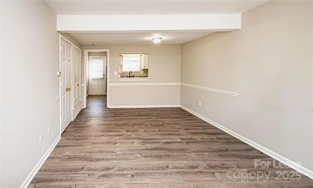 a view of a hallway with wooden floor and a kitchen space